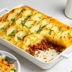 Zapiekanka ziemniaczana z warzywnym farszem, posypana natką pietruszki.