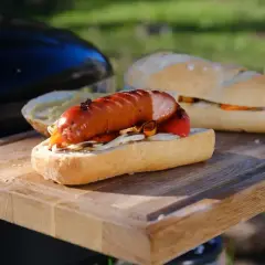 Pyszna kiełbasa z grilla w bułce z warzywami, gotowa do jedzenia na świeżym powietrzu.
