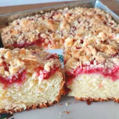 Puszysta babka z truskawkami i kruszonką, pokrojona na dwa kawałki, prezentuje się apetycznie.