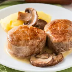 Dwie soczyste polędwiczki wieprzowe w sosie z pieczarkami i puree ziemniaczanym.