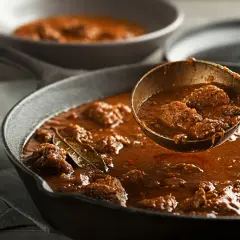 Gęsty, aromatyczny gulasz wołowy w żeliwnej patelni, gotowy do podania. Idealny przykład, jak zagęścić gulasz, by był sycący i pyszny.
