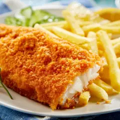 Chrupiący filet po parysku z frytkami i cytryną, ozdobiony gałązką koperku.
