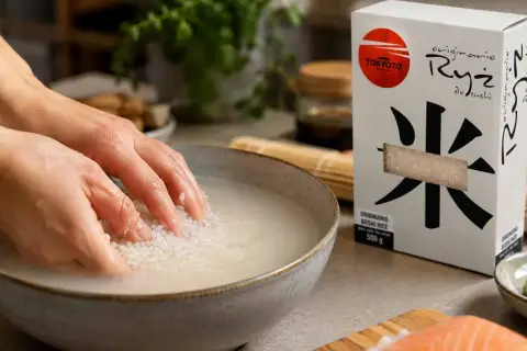 Ręce płuczą ryż do sushi w misce, przygotowując go do gotowania. Obok pudełko ryżu i łosoś.