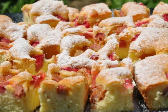 Szybkie ciasto z rabarbarem, pokrojone w kostkę i posypane cukrem pudrem, wygląda apetycznie. Idealne na letnie popołudnie.