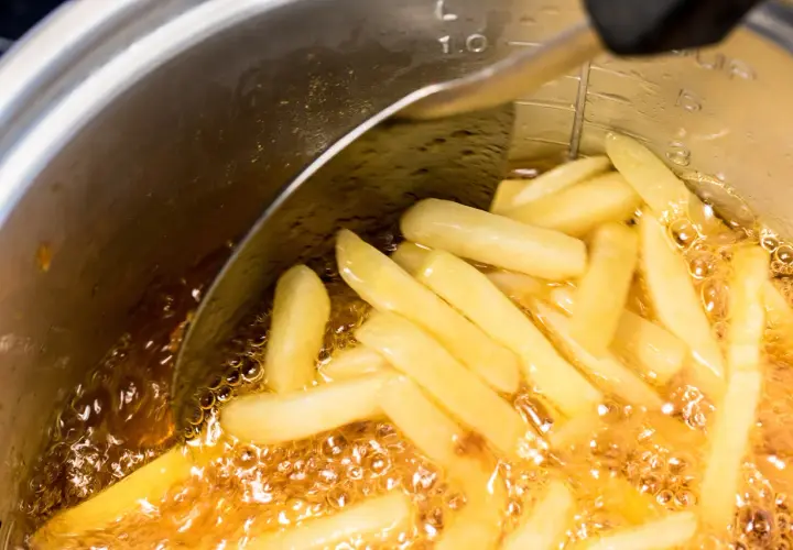 Frytki smażące się w głębokim oleju w garnku.