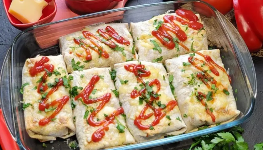 Zapiekana tortilla z mięsem mielonym, serem i ketchupem, posypana natką pietruszki, w szklanym naczyniu.