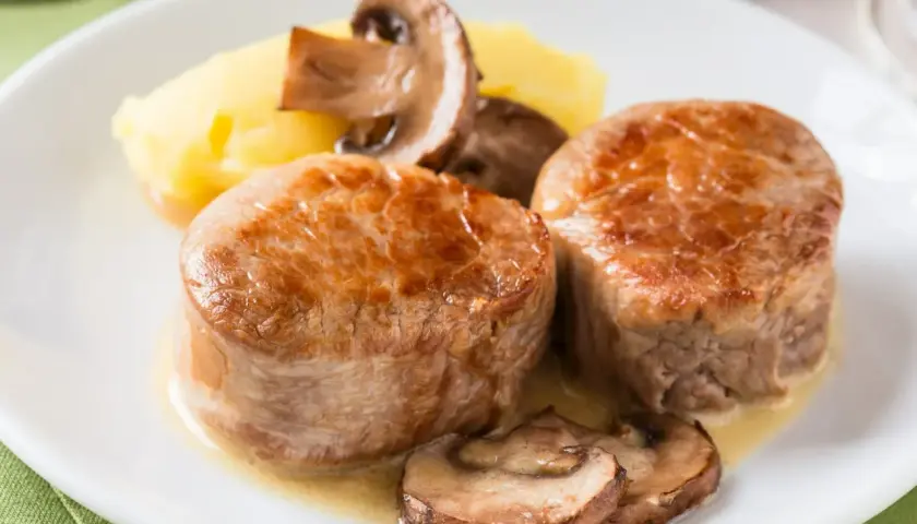 Dwie soczyste polędwiczki wieprzowe w sosie z pieczarkami i puree ziemniaczanym.