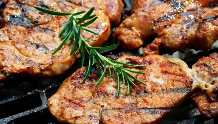 Soczyste plastry karkówki, idealnie przypieczone na grillu, z gałązką rozmarynu. To efekt doskonałej marynaty do karkówki.
