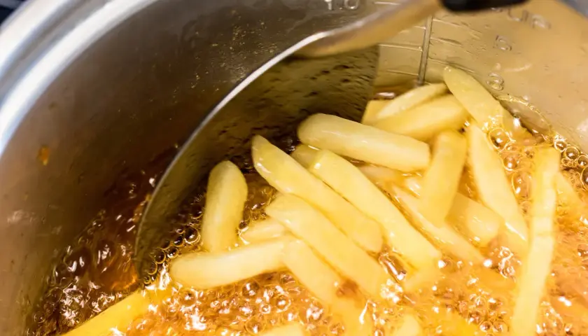Frytki smażące się w głębokim oleju w garnku.