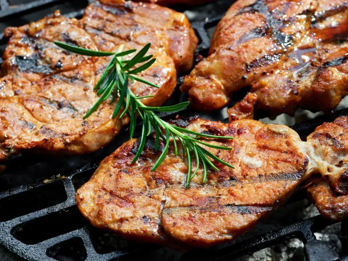 Soczyste plastry karkówki, idealnie przypieczone na grillu, z gałązką rozmarynu. To efekt doskonałej marynaty do karkówki.