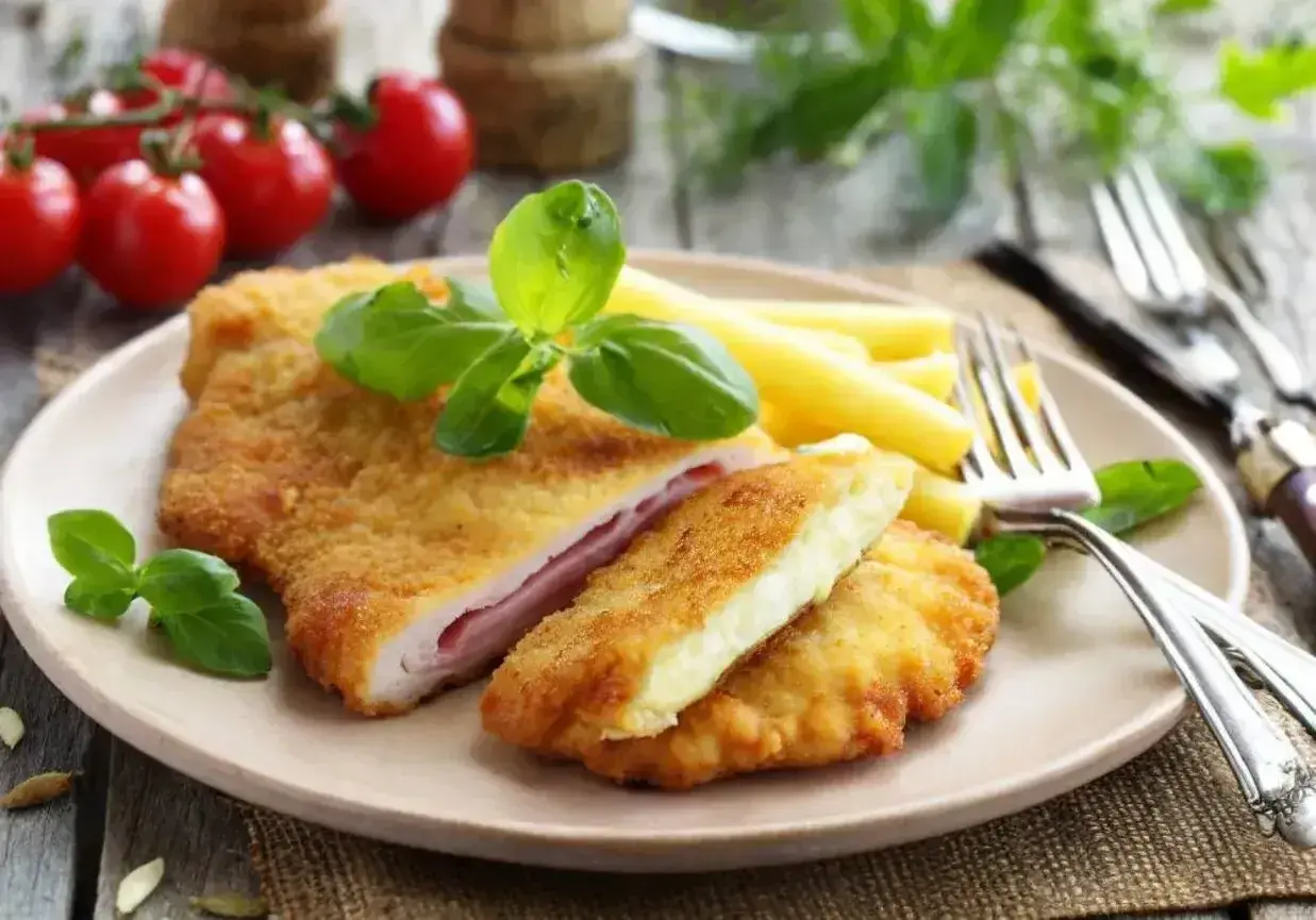 Schab po szwajcarsku z serem i szynką, panierowany, podany z makaronem i bazylią.