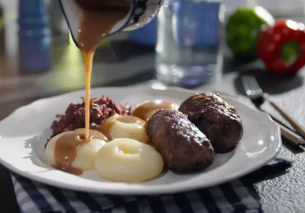 Sos spływa na kluski śląskie, obok czerwona kapusta i pieczone rolady śląskie. Pyszny obiad!