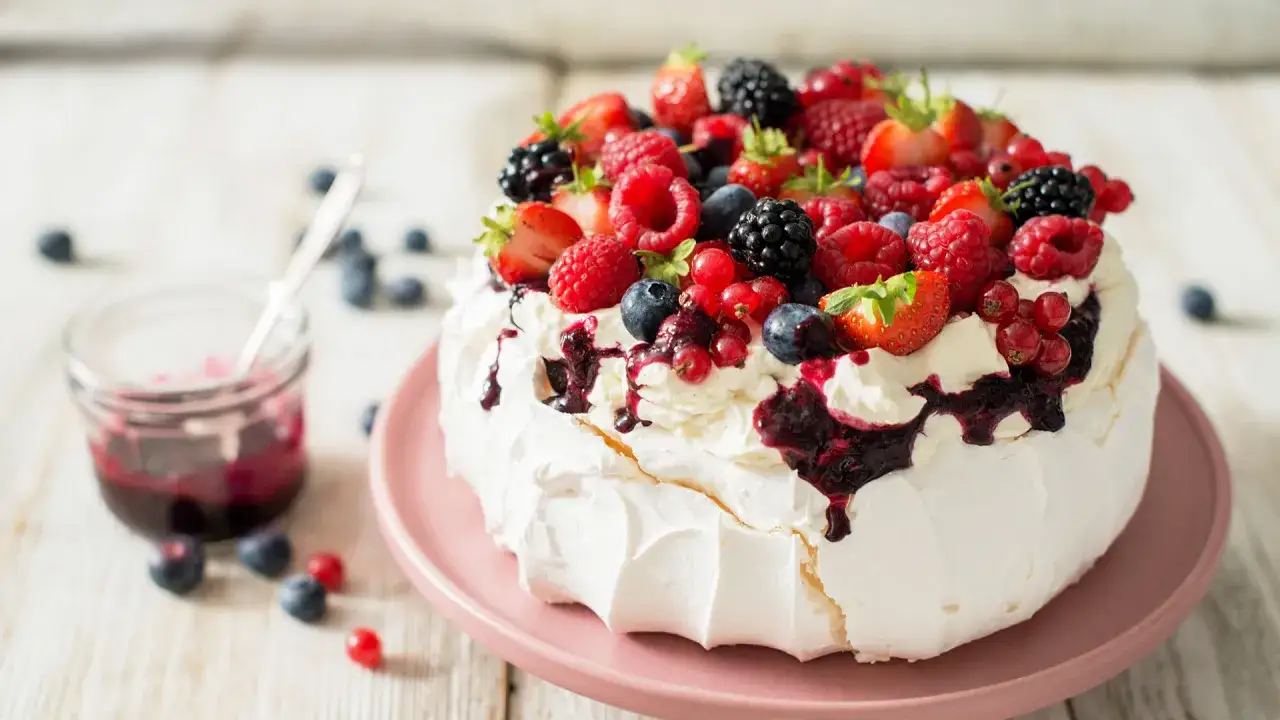 Pyszny deser Pavlova z bitą śmietaną i owocami leśnymi. Idealny sposób, by wykorzystać co zrobić z białek!