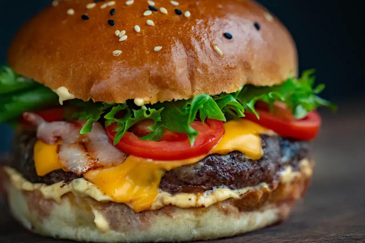 Soczysty burger z serem, bekonem i warzywami. Idealny przykład, jak przyprawić mięso na hamburgery, by było pyszne.